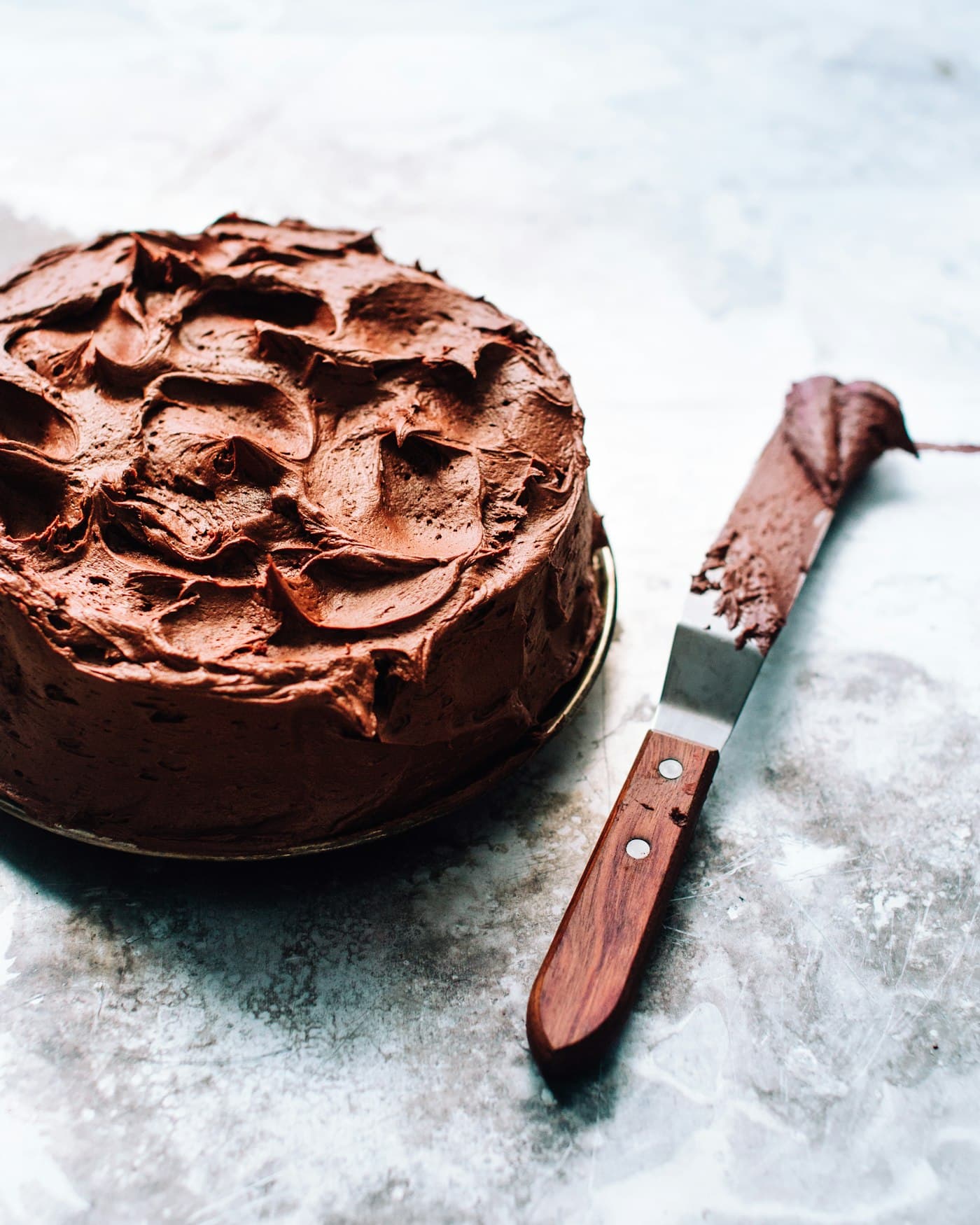 Bizcocho de chocolate con cobertura en remolinos y una espátula