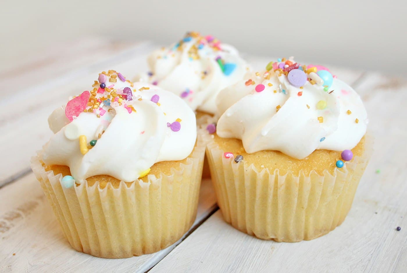 Cupcakes de vainilla con crema blanca y chispas de colores