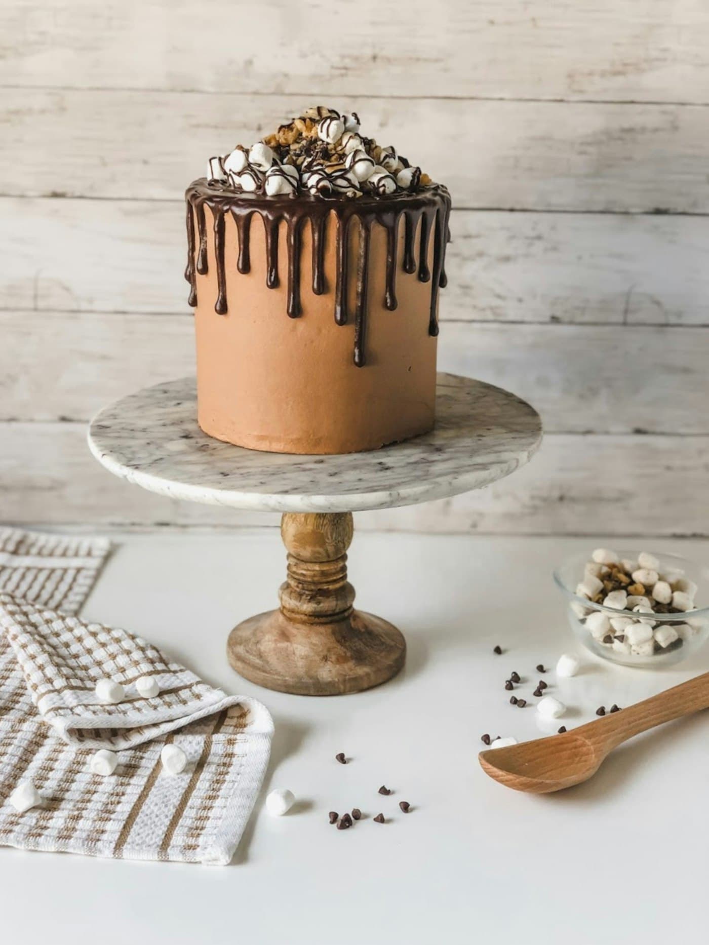 Bizcocho de chocolate con goteo y toppings sobre una base de mármol
