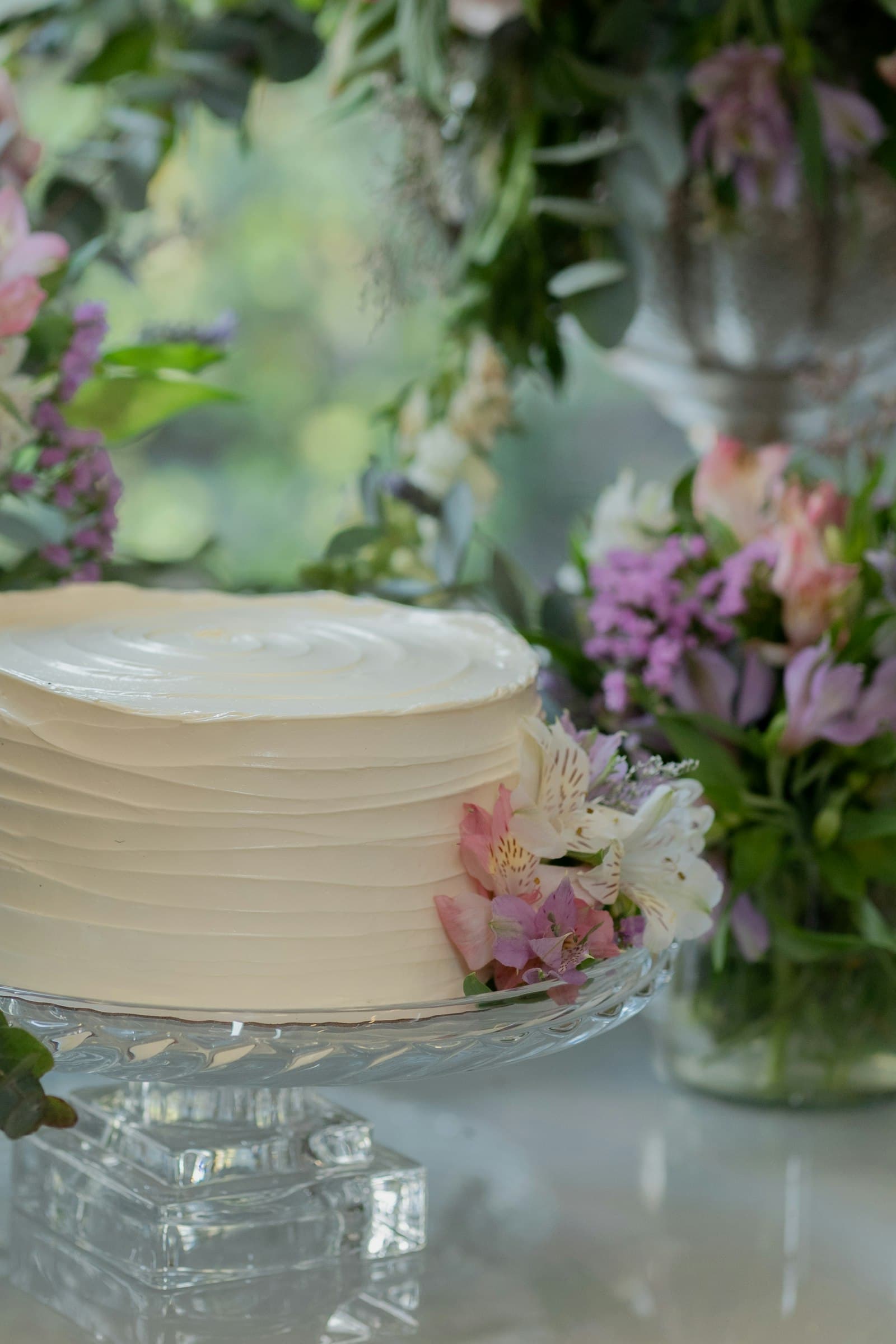 Bizcocho blanco con flores naturales sobre una base de cristal
